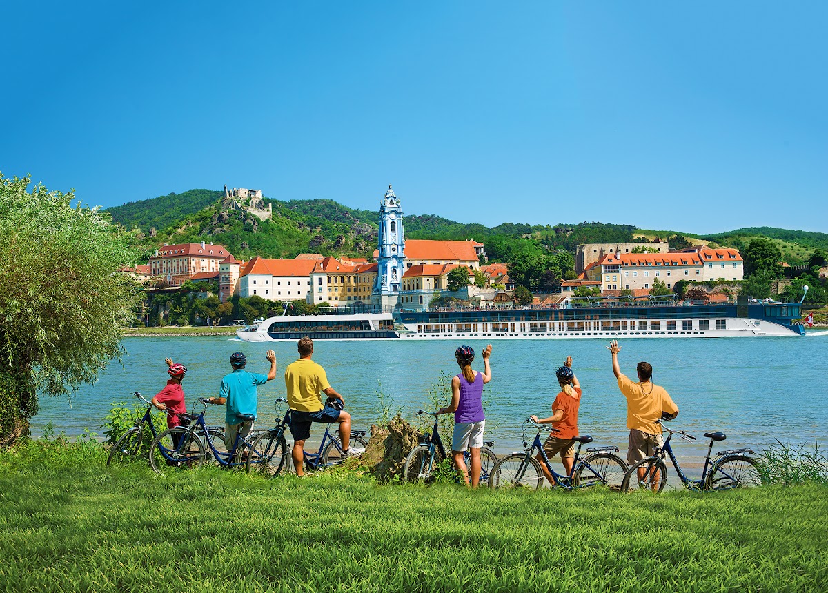Cyclists riding past Durnstein on a Danube river cruise